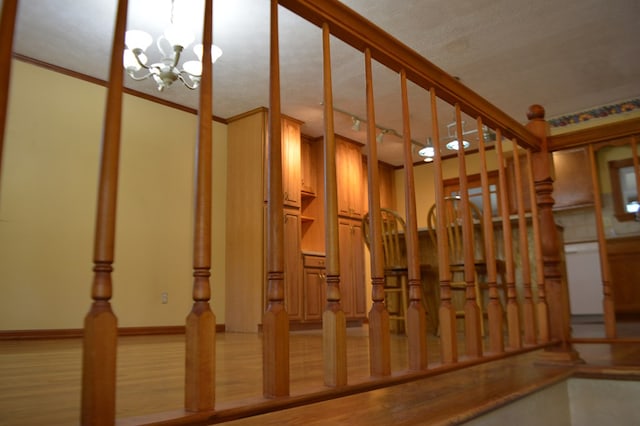 interior space with a textured ceiling, a notable chandelier, wood-type flooring, and crown molding