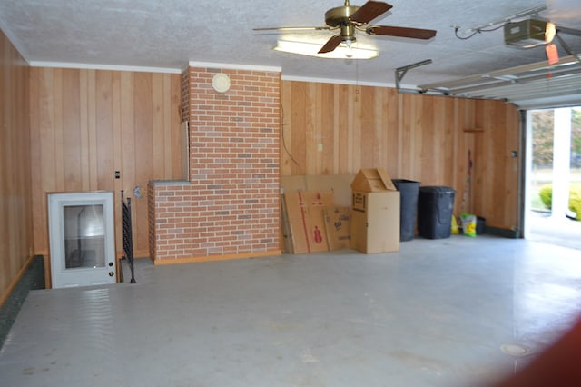 garage featuring wood walls, ceiling fan, and a garage door opener