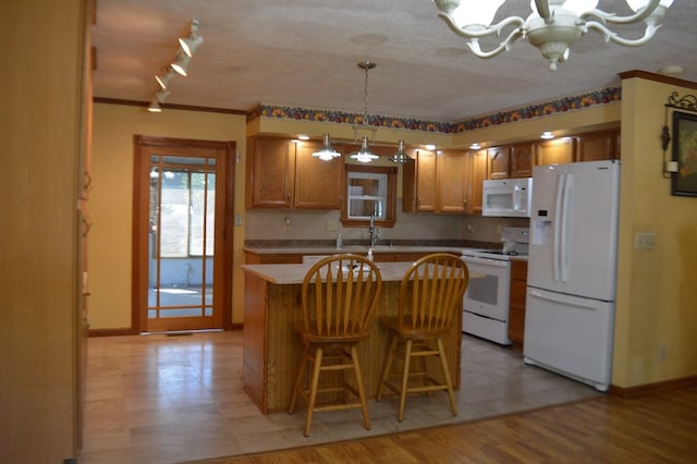 kitchen with pendant lighting, white appliances, light wood-type flooring, a notable chandelier, and a kitchen island