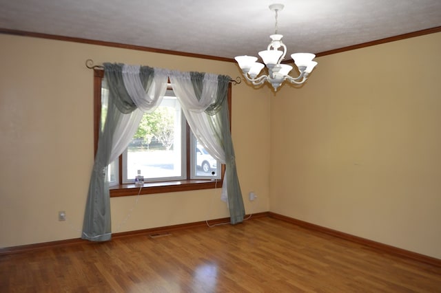 unfurnished room with hardwood / wood-style floors, ornamental molding, a textured ceiling, and an inviting chandelier