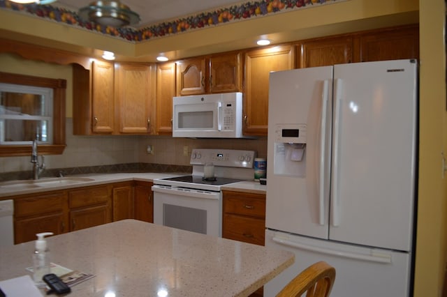 kitchen with tasteful backsplash, light stone counters, sink, and white appliances