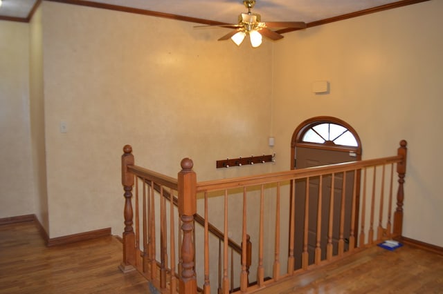 stairs with ceiling fan, wood-type flooring, and crown molding