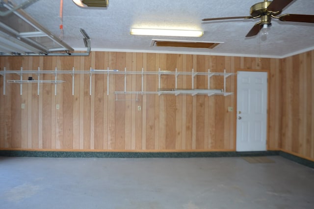 garage featuring ceiling fan and wood walls