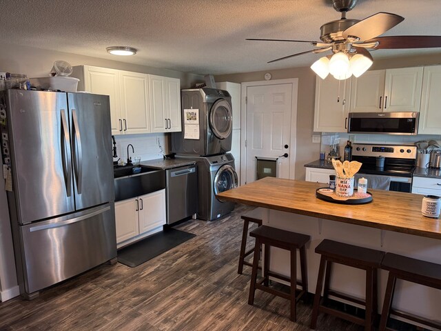 1421 Cullen Ave, Bucyrus, OH 44820 - kitchen with wood counters, appliances with stainless steel finishes, white cabinets, a sink, and stacked washing maching and dryer