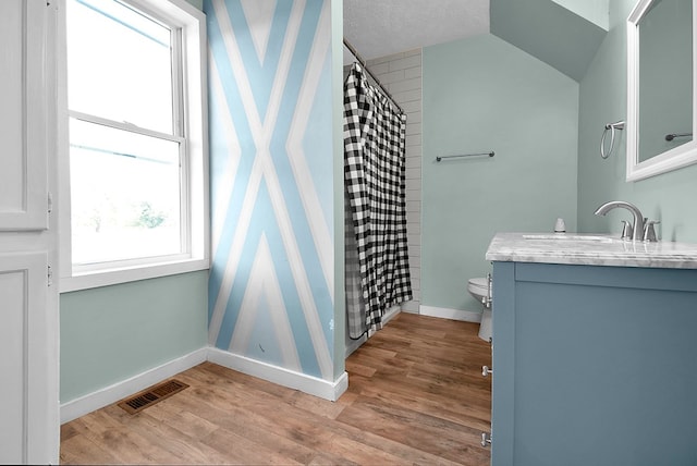 bathroom with visible vents, toilet, vaulted ceiling, vanity, and wood finished floors