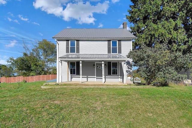 traditional home with a chimney, a porch, metal roof, fence, and a front lawn