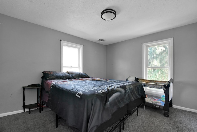 bedroom with a textured ceiling, multiple windows, visible vents, and carpet flooring