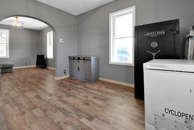 laundry room featuring baseboards, arched walkways, and wood finished floors