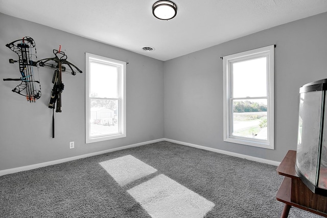 unfurnished room with baseboards, carpet floors, visible vents, and a healthy amount of sunlight