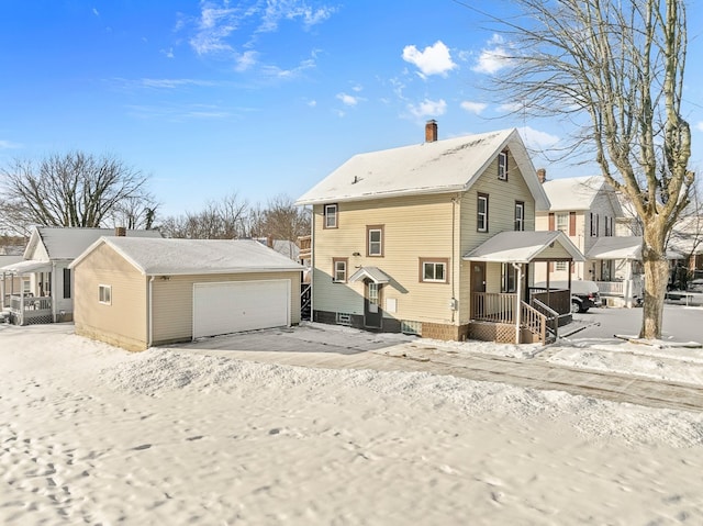 snow covered back of property featuring a garage and an outdoor structure