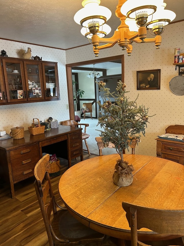 dining area with dark wood-type flooring, a notable chandelier, crown molding, and a textured ceiling