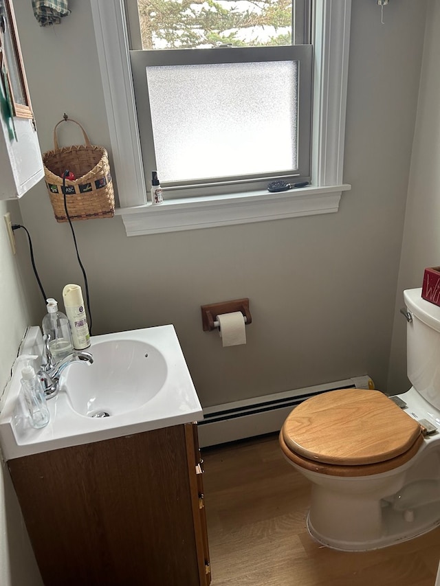 bathroom with wood-type flooring, a baseboard heating unit, vanity, and toilet