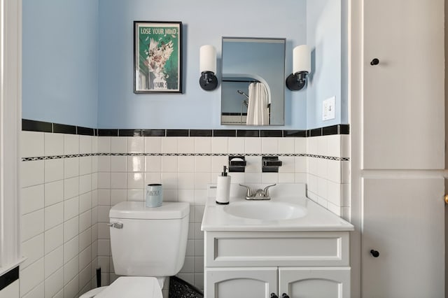 bathroom featuring toilet, tile walls, and vanity