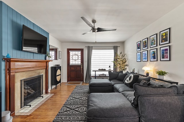 living room featuring light wood-type flooring, ceiling fan, and a fireplace