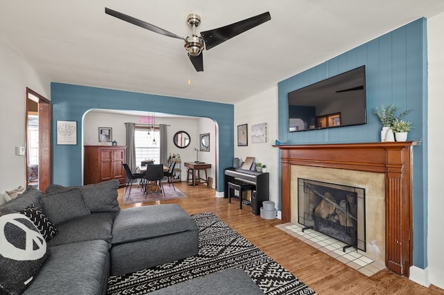 living room featuring ceiling fan, hardwood / wood-style floors, and a tile fireplace