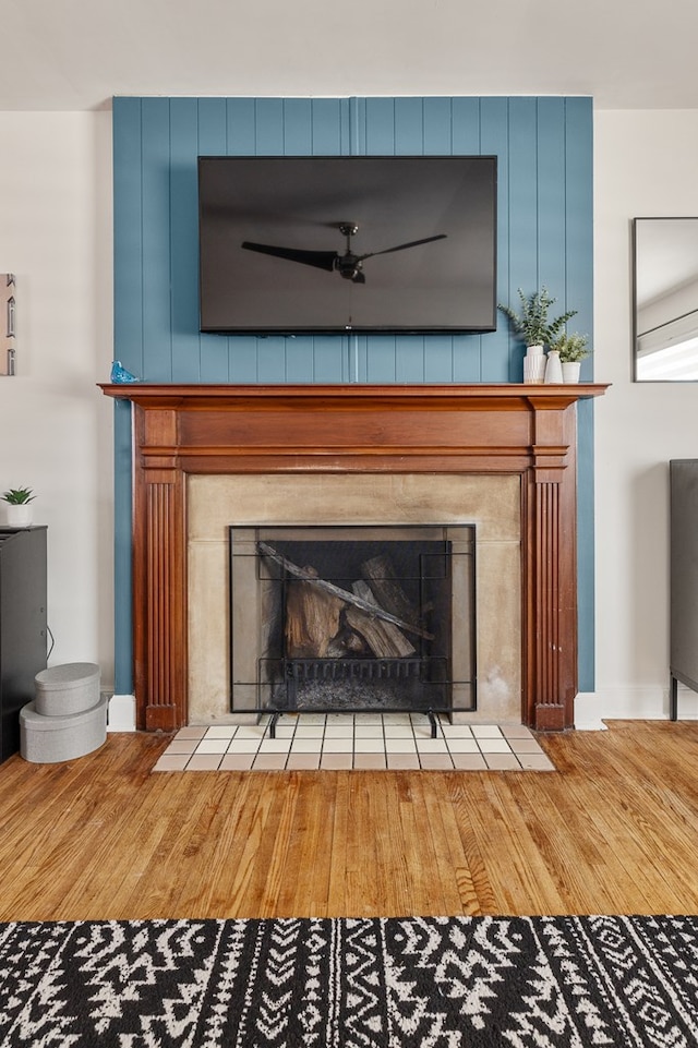 details with hardwood / wood-style flooring, ceiling fan, and a tiled fireplace