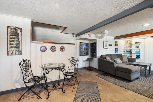 dining room featuring beam ceiling, wood walls, and a textured ceiling