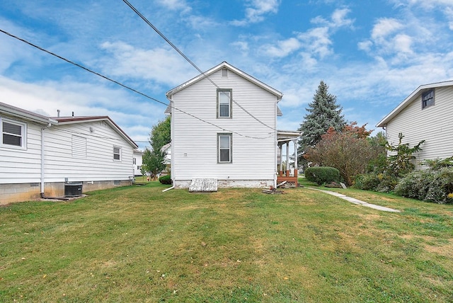 rear view of house with central air condition unit and a lawn