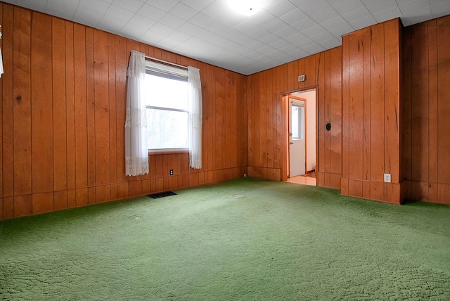 unfurnished room featuring light carpet and wood walls