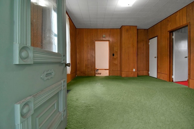 carpeted empty room featuring wooden walls