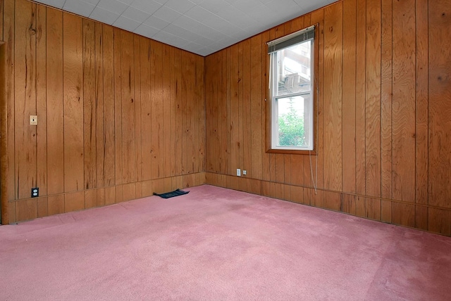 carpeted spare room with wooden walls