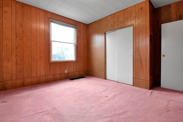 unfurnished bedroom with wood walls and light colored carpet