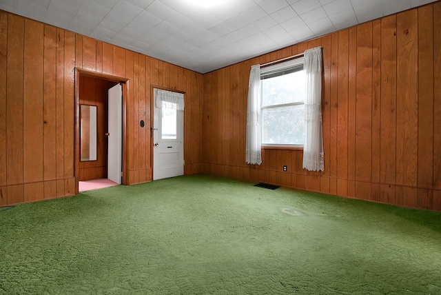 spare room with carpet and wood walls