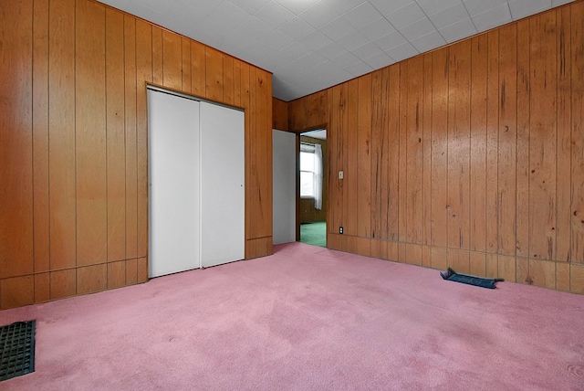 unfurnished bedroom featuring wood walls and light carpet