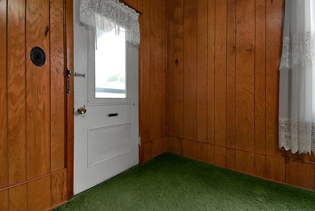 entryway with wooden walls and carpet floors