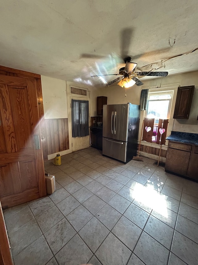 1221 N Sandusky Ave, Bucyrus, OH 44820 - kitchen featuring freestanding refrigerator, a ceiling fan, dark countertops, wainscoting, and wood walls