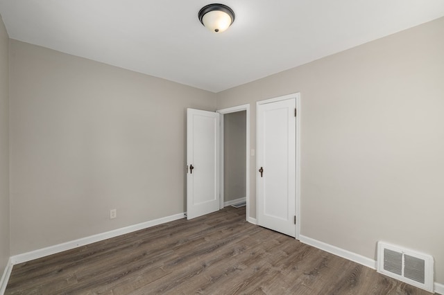 unfurnished room featuring visible vents, baseboards, and wood finished floors