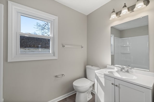 bathroom with baseboards, toilet, walk in shower, and vanity