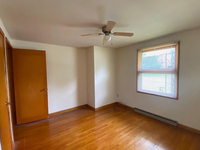 empty room featuring ceiling fan, a baseboard radiator, and light wood-type flooring