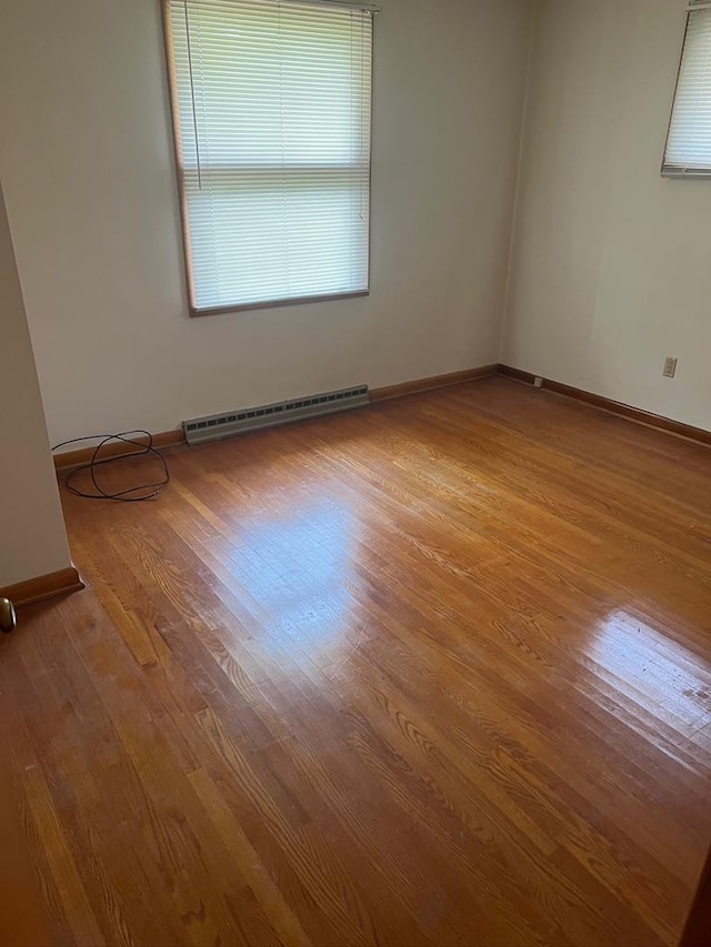 empty room with a baseboard heating unit and light wood-type flooring