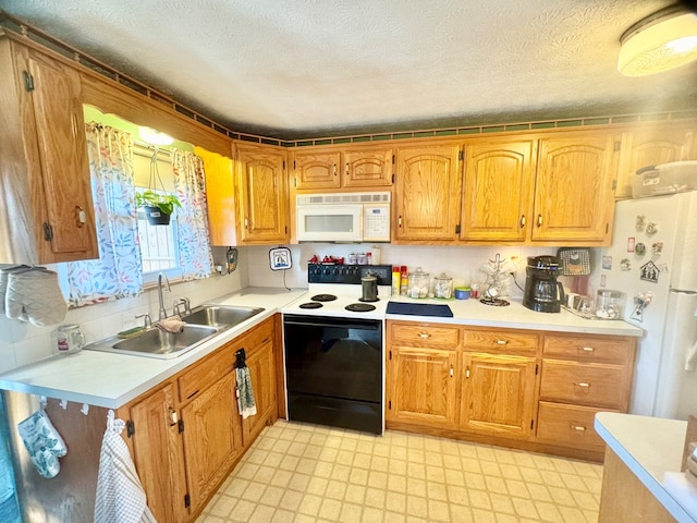 kitchen featuring light countertops, white appliances, a textured ceiling, a sink, and light floors