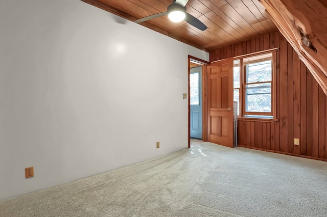 spare room featuring wooden walls, carpet flooring, wood ceiling, and a ceiling fan