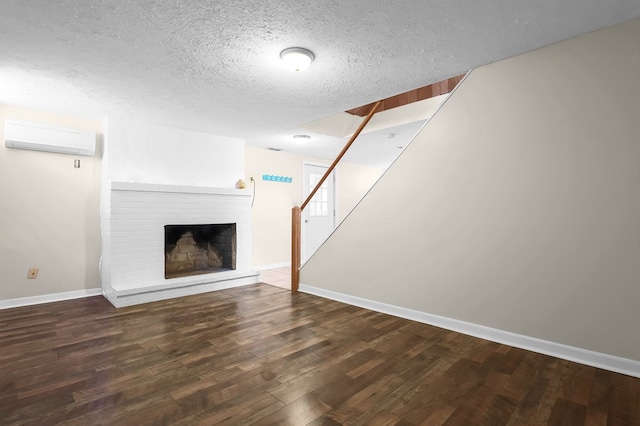 unfurnished living room featuring a textured ceiling, a brick fireplace, wood finished floors, stairs, and a wall mounted AC