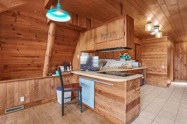 kitchen featuring visible vents, light countertops, wooden ceiling, and wood walls