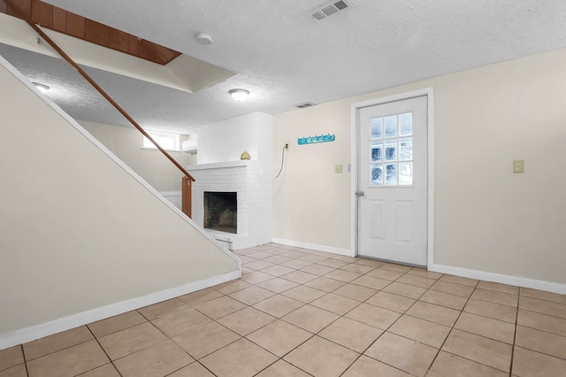 foyer with baseboards, visible vents, a textured ceiling, and light tile patterned flooring