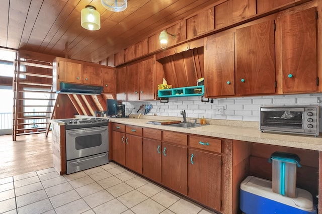 kitchen featuring light countertops, under cabinet range hood, a sink, and stainless steel range with electric stovetop