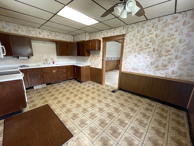 5655 Lime Rd, Galion, OH 44833 - kitchen featuring wallpapered walls, wainscoting, ceiling fan, stove, and a drop ceiling