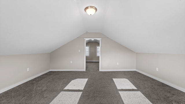 additional living space with dark carpet and vaulted ceiling