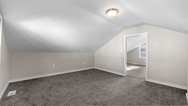 bonus room featuring dark colored carpet and vaulted ceiling