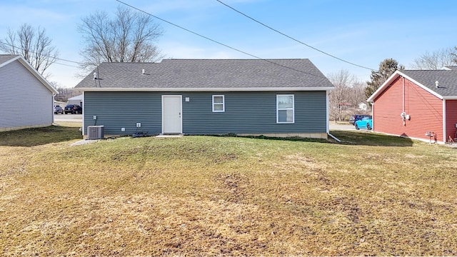 rear view of house with a lawn and roof with shingles