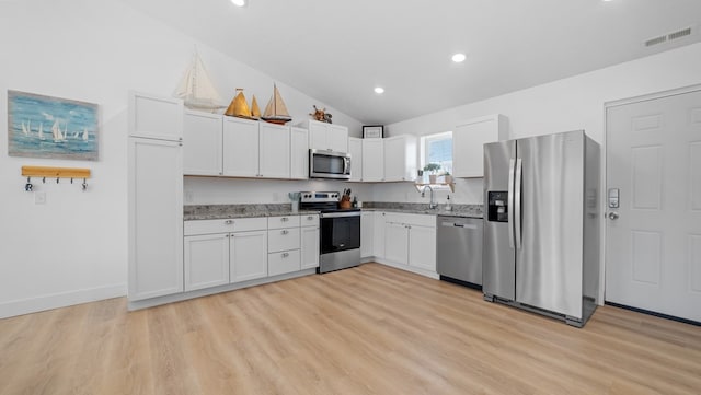 kitchen featuring stainless steel appliances, visible vents, light wood-style flooring, white cabinetry, and light stone countertops