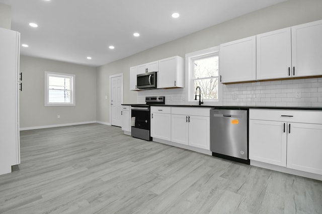 kitchen with stainless steel appliances, tasteful backsplash, and white cabinets