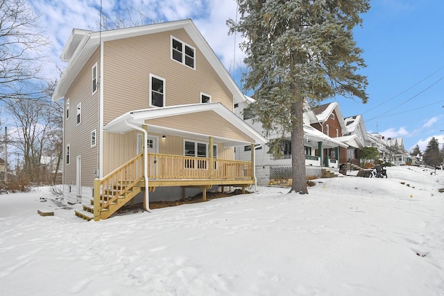 snow covered back of property featuring a porch