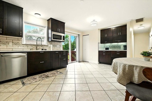 1645 Spring Village Ln, Mansfield, OH 44906 - kitchen with appliances with stainless steel finishes, decorative backsplash, light countertops, light tile patterned floors, and dark brown cabinets
