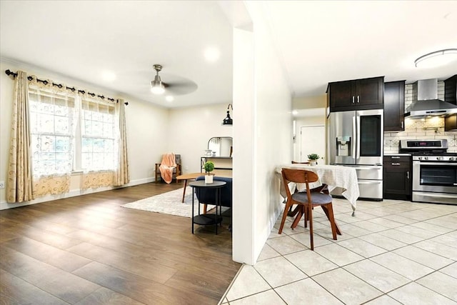 1645 Spring Village Ln, Mansfield, OH 44906 - kitchen with appliances with stainless steel finishes, wall chimney exhaust hood, light wood-type flooring, ceiling fan, and tasteful backsplash