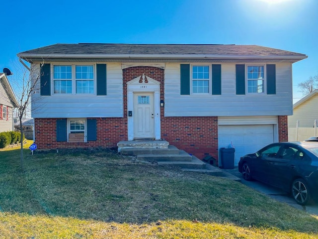 raised ranch with a front yard, a garage, and brick siding